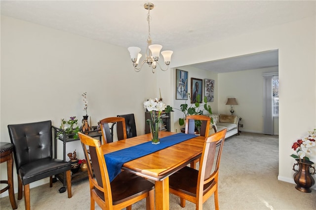 dining area featuring light carpet and a chandelier