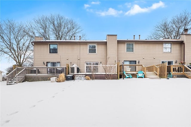 snow covered back of property featuring a deck