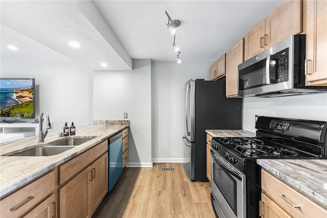 kitchen featuring sink, stainless steel appliances, light hardwood / wood-style floors, and light stone countertops