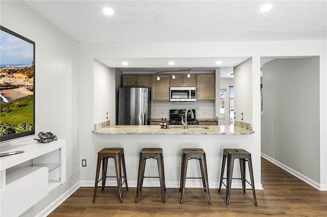 kitchen featuring appliances with stainless steel finishes, a kitchen breakfast bar, dark hardwood / wood-style flooring, and sink