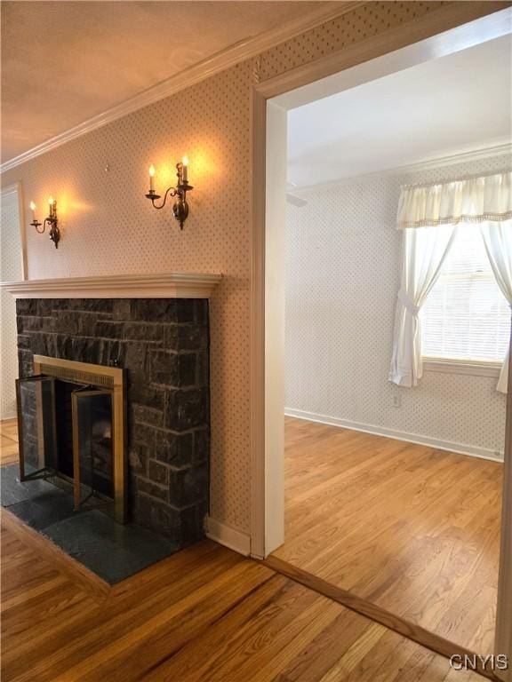 unfurnished living room featuring hardwood / wood-style flooring, a stone fireplace, and ornamental molding