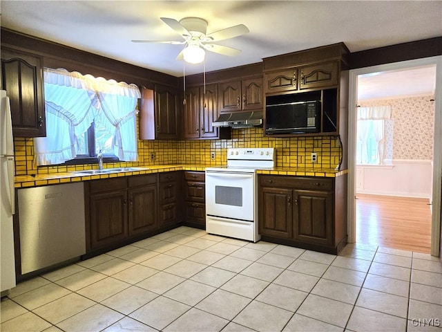kitchen with sink, white appliances, ceiling fan, dark brown cabinets, and tile counters