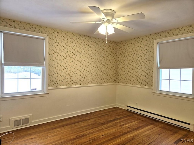 unfurnished room featuring a baseboard heating unit, dark wood-type flooring, and ceiling fan