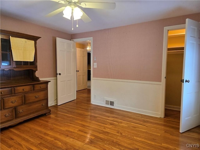 bedroom with ceiling fan, a walk in closet, and light wood-type flooring