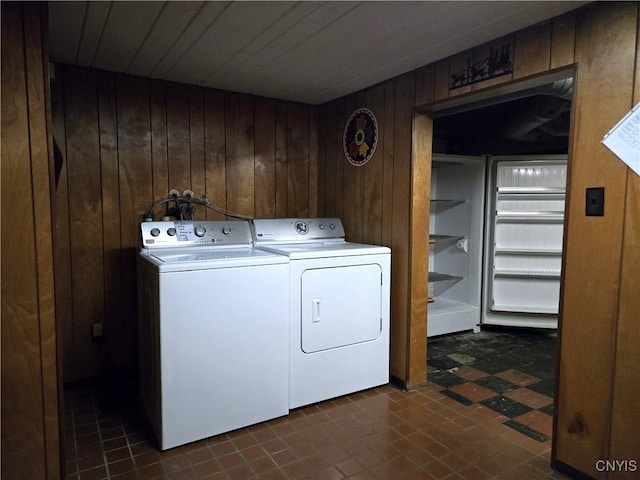 laundry area featuring washing machine and clothes dryer and wood walls