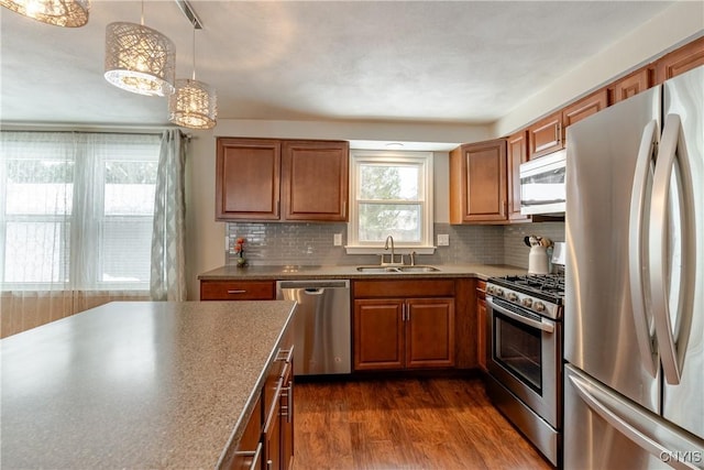 kitchen featuring sink, dark hardwood / wood-style flooring, pendant lighting, stainless steel appliances, and backsplash