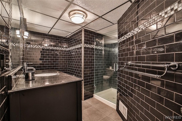 bathroom featuring vanity, a shower with shower door, tile patterned floors, and a drop ceiling