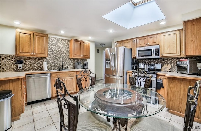 kitchen featuring sink, backsplash, a skylight, and stainless steel appliances