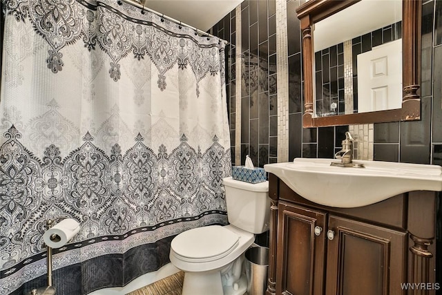 bathroom featuring vanity, tile walls, and toilet