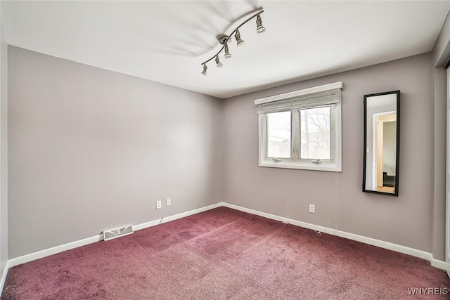 carpeted spare room featuring track lighting