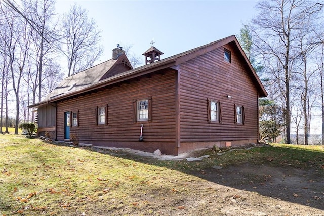 view of side of home featuring entry steps, a lawn, and a chimney