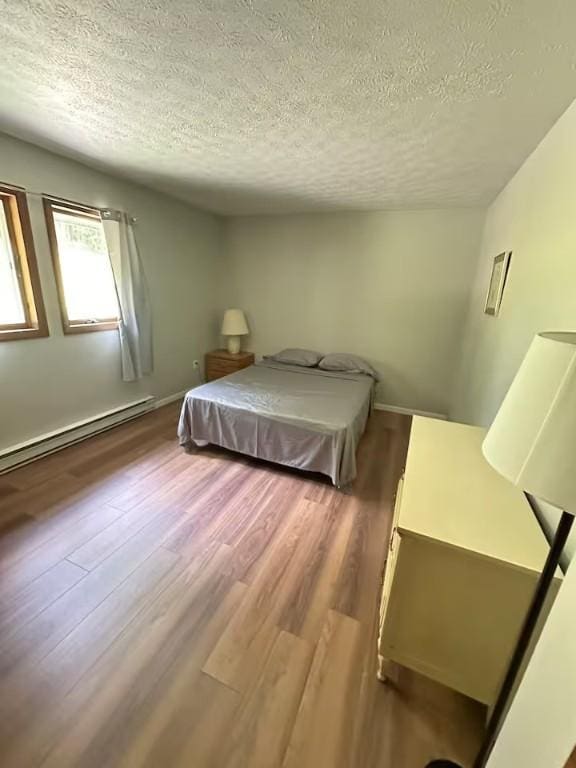 bedroom featuring hardwood / wood-style flooring, a textured ceiling, and a baseboard heating unit