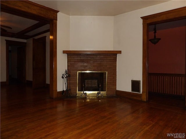 unfurnished living room featuring a brick fireplace and dark wood-type flooring