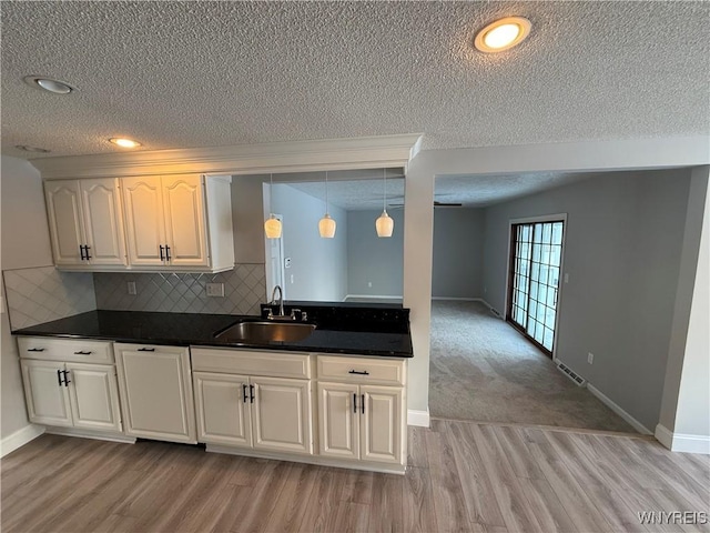 kitchen featuring pendant lighting, sink, light hardwood / wood-style flooring, white cabinetry, and tasteful backsplash