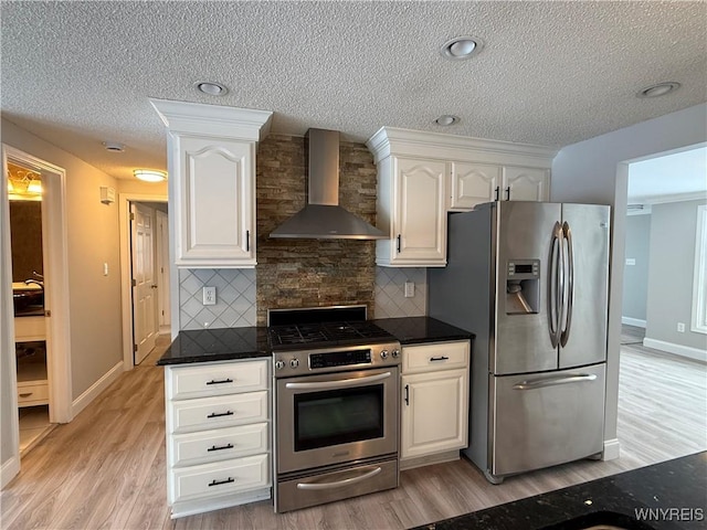 kitchen featuring white cabinetry, tasteful backsplash, stainless steel appliances, and wall chimney exhaust hood