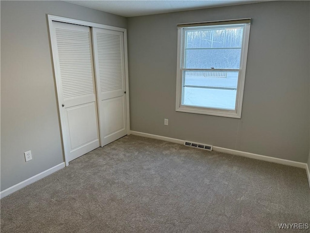 unfurnished bedroom with light colored carpet and a closet