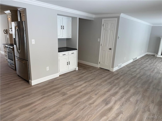 kitchen featuring white cabinetry, crown molding, light hardwood / wood-style flooring, and stainless steel appliances