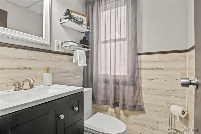 bathroom with vanity, toilet, and a drop ceiling