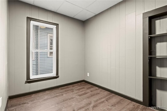 spare room with a drop ceiling and light hardwood / wood-style floors