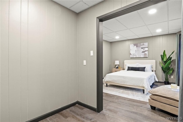 bedroom with hardwood / wood-style floors and a paneled ceiling