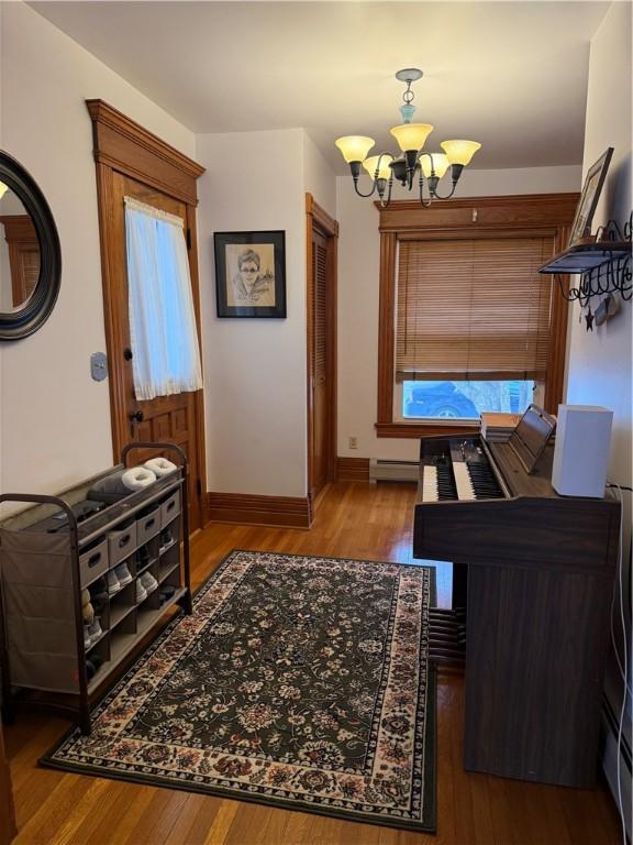 interior space with hardwood / wood-style flooring, a chandelier, and a baseboard heating unit