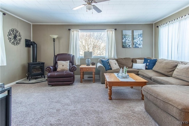 carpeted living room with ceiling fan, ornamental molding, a wood stove, and a healthy amount of sunlight