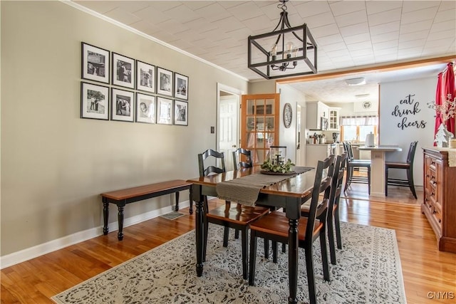 dining area featuring ornamental molding, a chandelier, and light hardwood / wood-style flooring