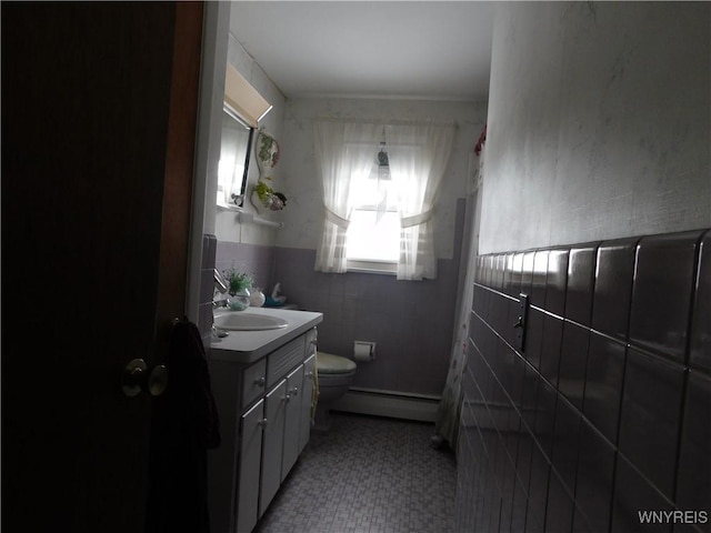 bathroom featuring tile patterned flooring, baseboard heating, toilet, tile walls, and vanity