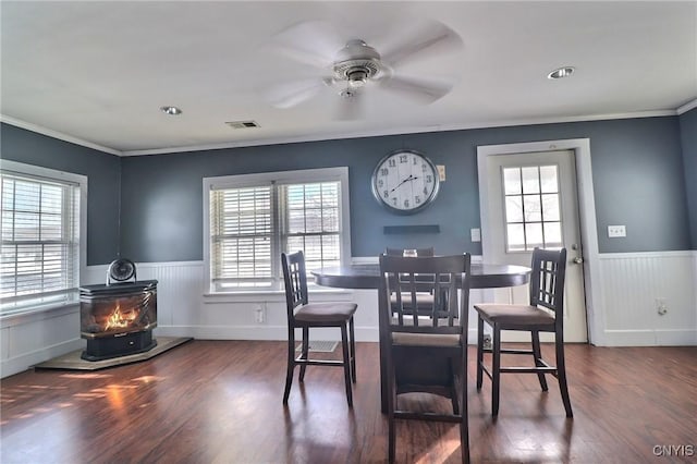 dining room with a wood stove, a wealth of natural light, and dark hardwood / wood-style flooring