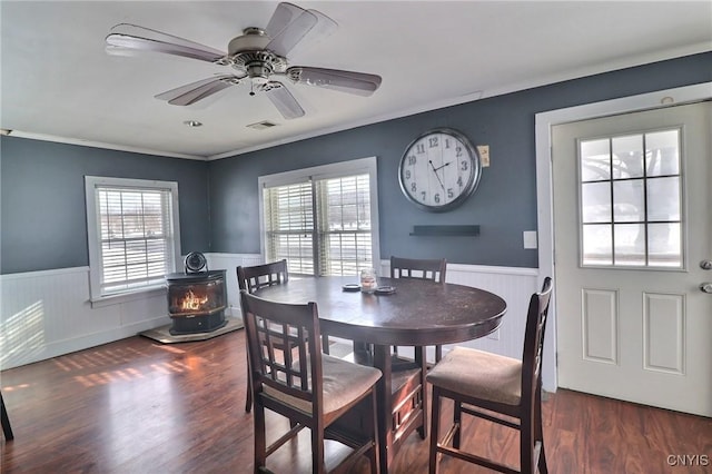 dining space with ceiling fan, ornamental molding, a wood stove, and dark hardwood / wood-style flooring