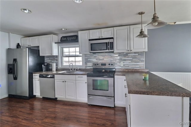 kitchen featuring white cabinetry, hanging light fixtures, sink, appliances with stainless steel finishes, and dark hardwood / wood-style floors