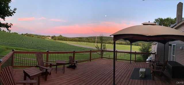 deck at dusk featuring a yard, a rural view, and a gazebo