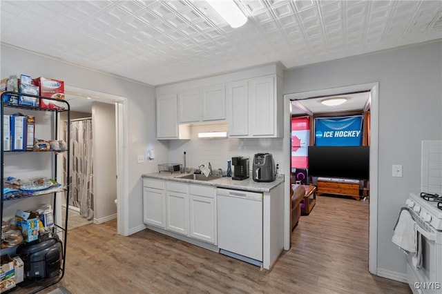 kitchen featuring white appliances, light hardwood / wood-style floors, backsplash, sink, and white cabinetry