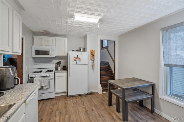 kitchen with white cabinetry, a healthy amount of sunlight, white appliances, and light hardwood / wood-style floors