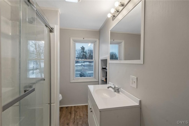 bathroom featuring hardwood / wood-style floors, vanity, an enclosed shower, toilet, and ornamental molding