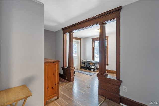 corridor with decorative columns and light hardwood / wood-style floors