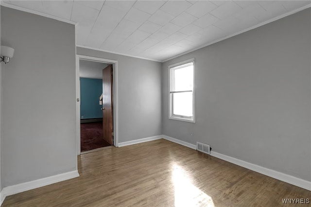 spare room with ornamental molding and wood-type flooring