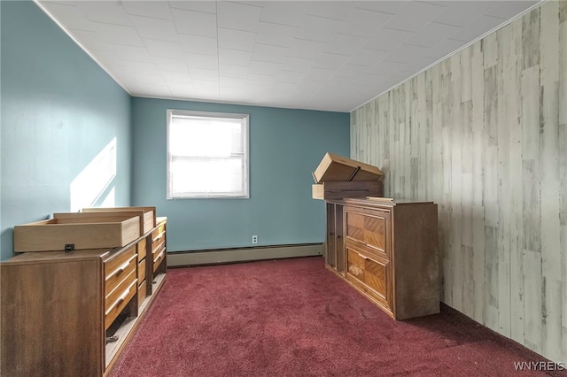 bedroom with dark carpet, baseboard heating, and wood walls