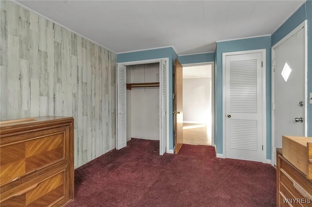 unfurnished bedroom with crown molding, dark colored carpet, and two closets