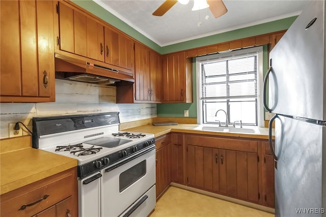 kitchen with stainless steel fridge, sink, tasteful backsplash, crown molding, and white range with gas cooktop