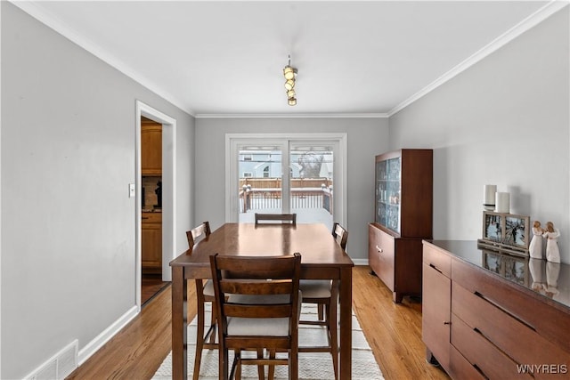 dining room with light hardwood / wood-style flooring and crown molding