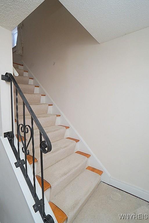 staircase featuring a textured ceiling