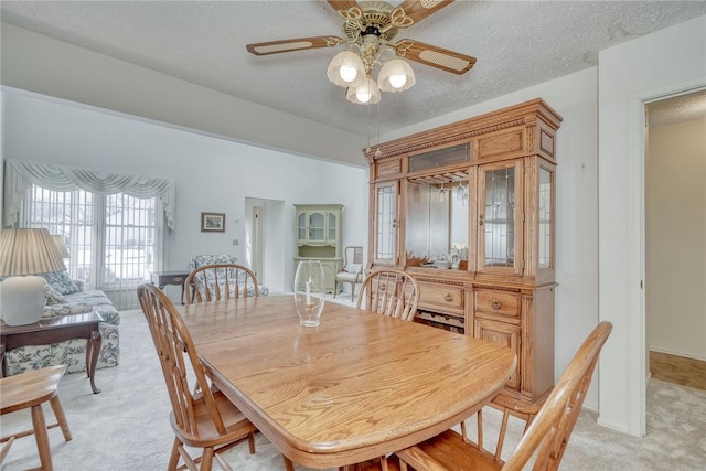 carpeted dining area featuring ceiling fan and a textured ceiling