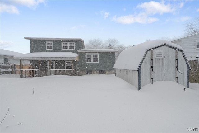 snow covered rear of property with an outdoor structure