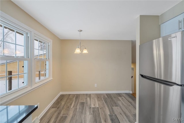 unfurnished dining area with light wood-type flooring and an inviting chandelier