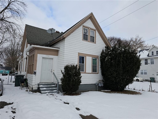 view of front facade featuring fence, roof with shingles, and entry steps