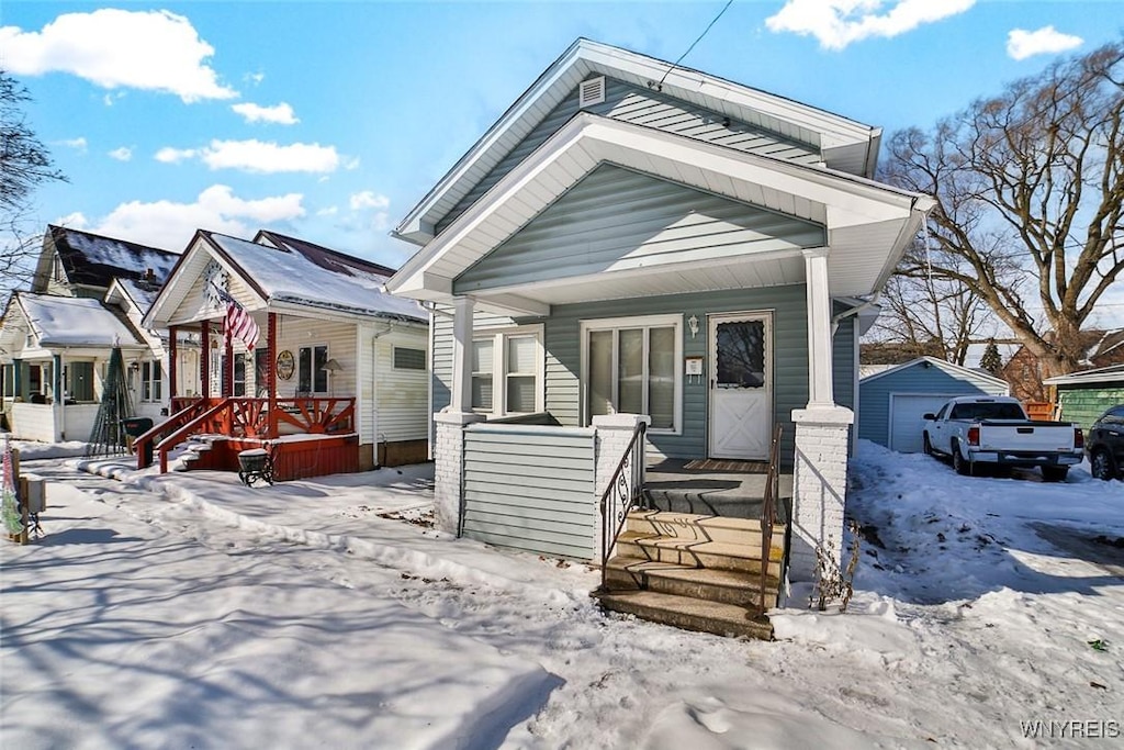 bungalow-style home featuring a garage, an outbuilding, and covered porch