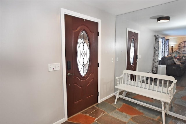 foyer with baseboards and stone tile flooring