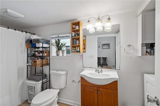 bathroom featuring a notable chandelier, vanity, toilet, and washer / clothes dryer