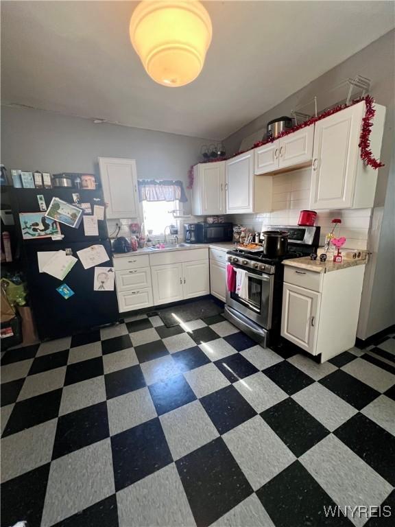 kitchen with white cabinetry, tasteful backsplash, sink, and stainless steel range with gas stovetop